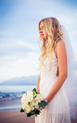 Fototapeta na wymiar beautiful bride standing by the beach at sunset