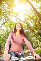 smiling  asian young woman riding bike in the forest