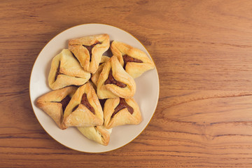 Hamantaschen cookies on plate over wooden table