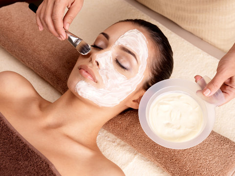 Spa therapy for woman receiving facial mask