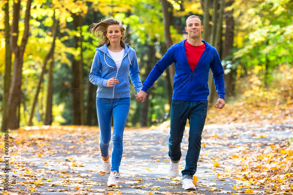 Wall mural Healthy lifestyle - woman and man running in park