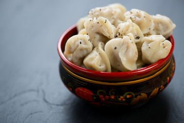 Boiled pelmeni with black pepper in russian khokhloma tableware