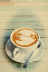 Hearts latte art coffee cup on grunge wood table in vintage styl