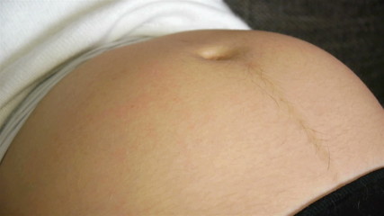 Baby kicking and moving in the mother belly close up