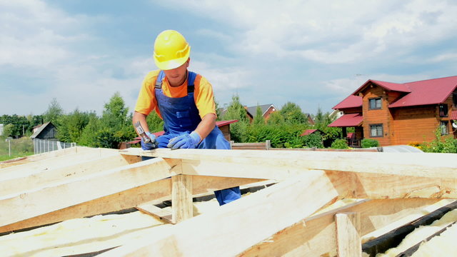 Roofer carpenter works on roof