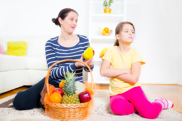 mother and daughter sit and pick fruit from the basket