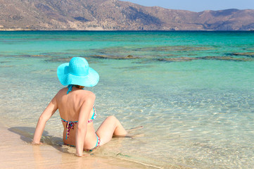 Fototapeta na wymiar Beautiful young woman with sunhat, relaxing on a sunny beach