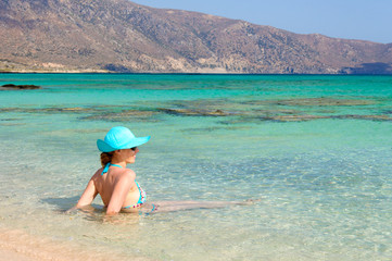 Beautiful young woman with sunhat, relaxing on a sunny beach