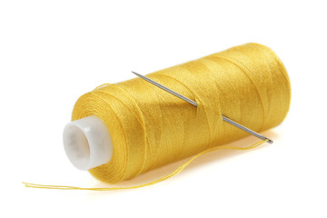 Yellow bobbin of thread with needle