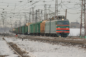 Fototapeta na wymiar Electric locomotive pulls the product composition of winter
