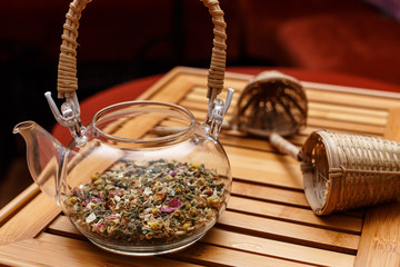 Glass teapot and two tea strainers on a red background