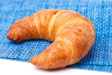 One croissant on blue linen