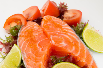 Raw salmon fillet with vegetables on white background