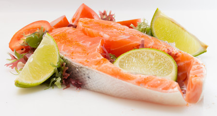 Raw salmon fillet with vegetables on white background