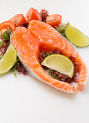 Raw salmon fillet with vegetables on white background
