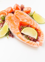 Raw salmon fillet with vegetables on white background