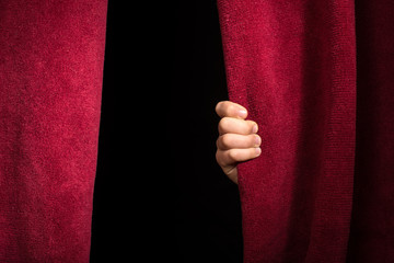 Hand appearing beneath the curtain.