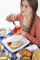 Junge Frau beim Frühstück - Brötchen mit Marmelade