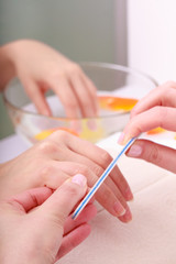 Beautician filing nails female client. Woman spa beauty salon