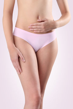 Woman's hands on stomach on pink background.