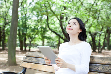 公園でタブレットPCを使う女性