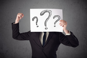 Businessman holding a paper with question marks in front of his