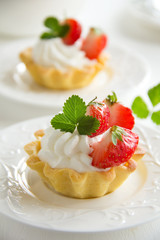 Tartlets with whipped cream and strawberries.