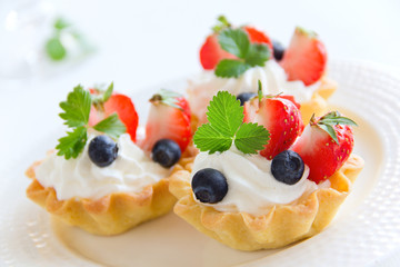 Tartlets with whipped cream and strawberries.