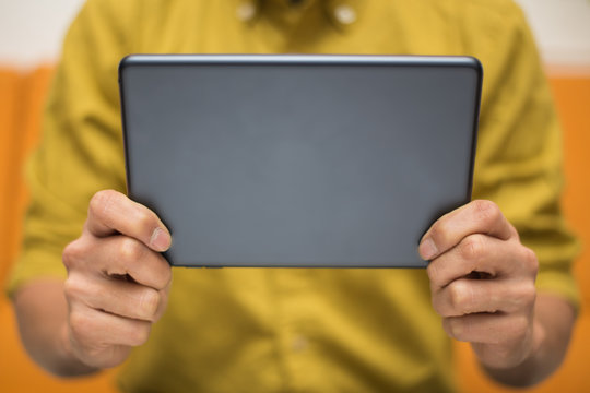 Close-up image of a man holding a digital tablet