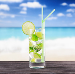 Glass of mojito cocktail on a beach