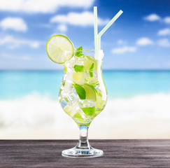 Glass of mojito cocktail on a beach