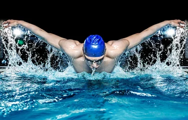Fotobehang Muscular young man in blue cap in swimming pool © Nejron Photo
