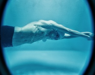 Man in swim cap and googles under water in swimming pool