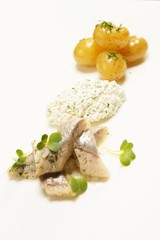 Fish slices with potato on a white plate