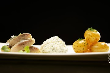 Fish slices with potato on a white plate