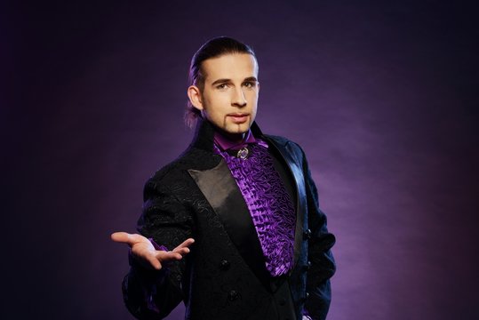 Young handsome brunette magician in stage costume
