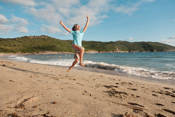 young boy playing running and jumping on the beach