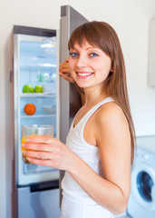 Young caucasian brunette girl with a glass of juice in the kitch