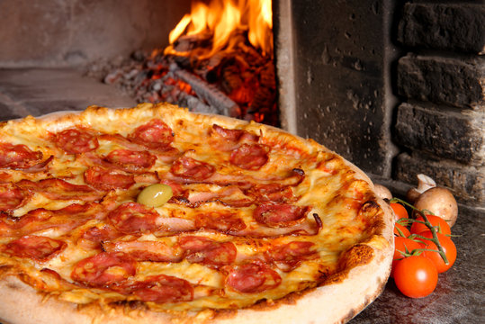 Baked tasty pizza with salami and bacon near oven