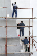 Workers at scaffolding spreading stucco over mortar, styrofoam