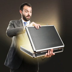 Young businessman open his briefcase over dark background