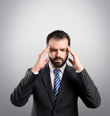 Young businessman with headache over grey background