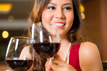 Chinese woman toasting in  restaurant with red wine 