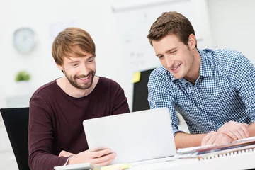 Fotobehang zwei kollegen schauen lachend auf laptop © contrastwerkstatt