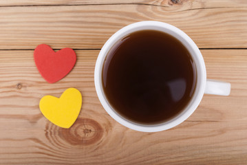 Cup of coffee and two hearts on a wooden background.