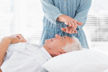 Obraz na płótnie Canvas Massage therapist performing Reiki over man