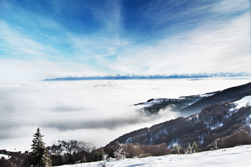 Fototapeta na wymiar Pejzaż zimowy, ośnieżone szczyty górskie i niskie chmury
