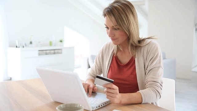 Cheerful middle-aged woman buying on internet