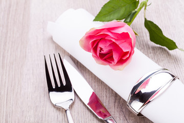 romantisch gedeckter tisch mit silberbesteck und einer rose