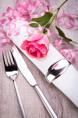 romantisch gedeckter tisch mit silberbesteck und einer rose